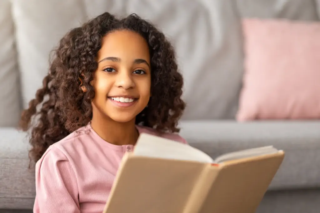 Smiling child reading book, after a stress-free Dental Extraction in Carrollton TX