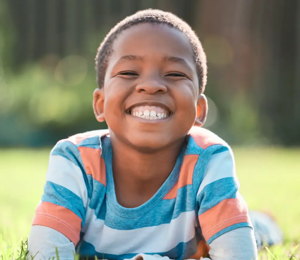 Confident child smiling outdoors, showing results of regular pediatric dental care