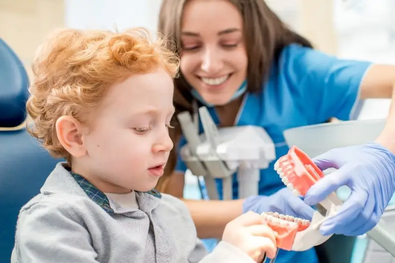 Pediatric dentist teaching child proper brushing with dental model in Carrollton, TX