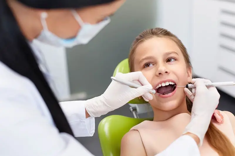 Dentist performing gentle dental checkup on child in Carrollton, TX