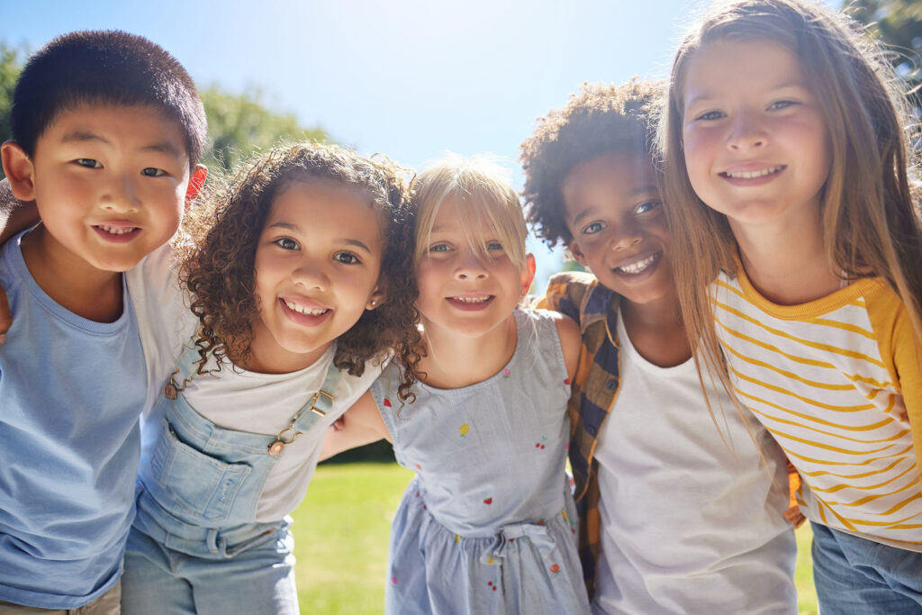 Smiling children outdoors showing healthy smiles after pediatric dental care