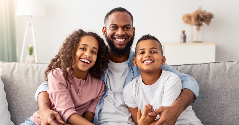 Father and children smiling happily, representing family-friendly dental care in Carrollton TX